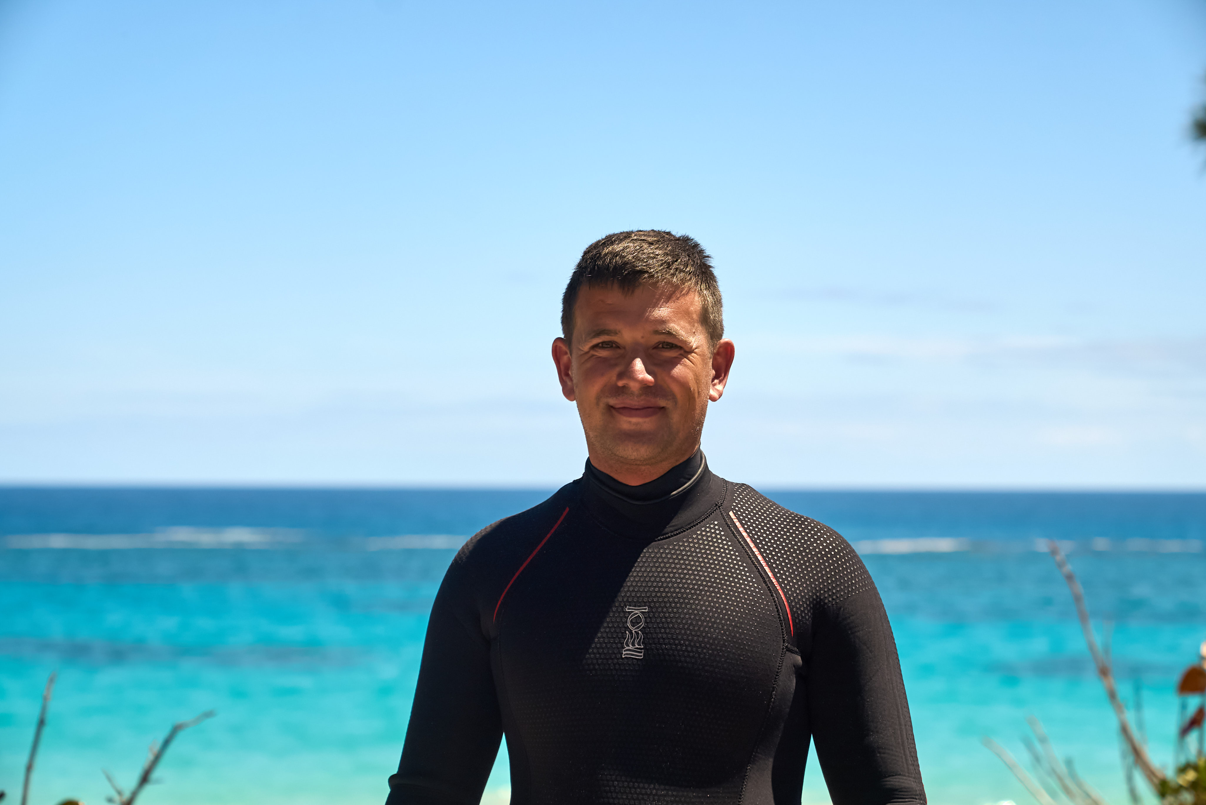 A man is smiling at the camera in scuba diving gear. 