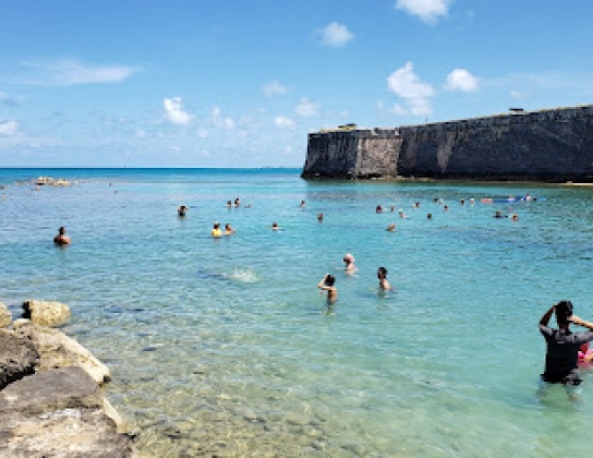 A shallow water area on a beach with a crowd of people swimming.