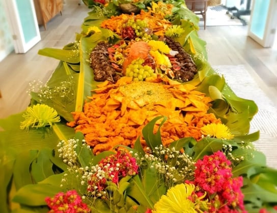 A colourful spread of fruits on a table covered in palm leaves.