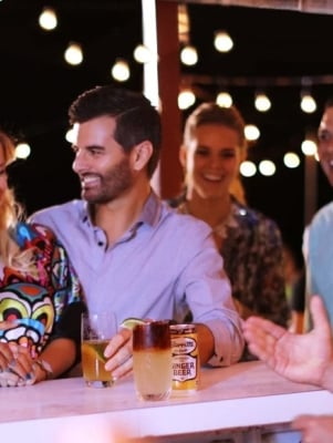 Bar scene with the focus on two girls and one guy laughing with drinks