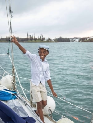 A little boy is smiling while walking on a boat.
