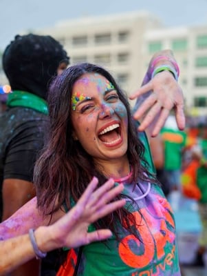 A woman is smiling at the camera with paint all over her.