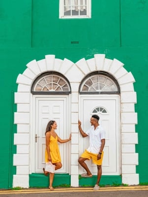 A couple is posing by a colourful building.