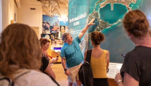 A man is showing people a map of the Bermuda Islands.
