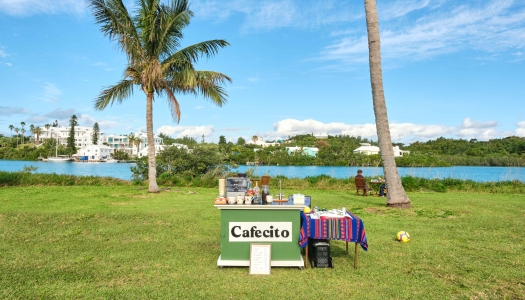 An outdoor coffee stand called Cafecito with a water view and seats in the background.