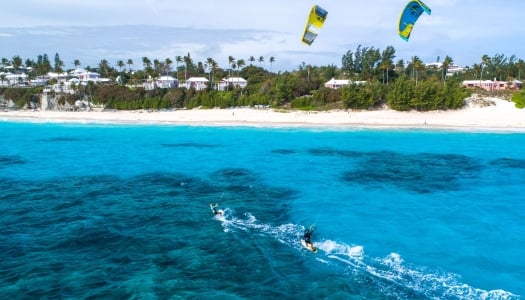 Two men are kite surfing in blue waters.
