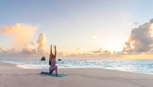 A woman is doing a yoga pose on the beach.