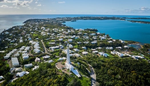 Aerial view of Gibbs Hill Lighthouse with calm waters and blue skies. 