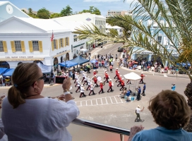 A group of people are looking down watching the Bermuda Day parade.