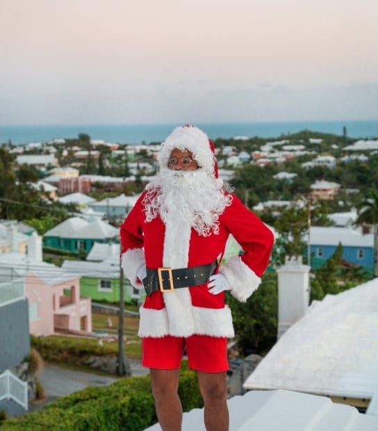 A man dressed as Santa is standing on a Bermuda house roof.