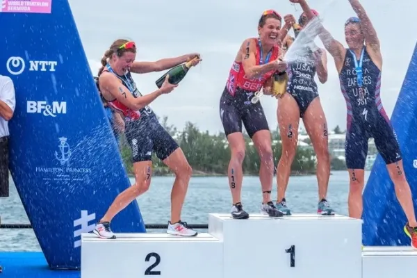 Triathletes celebrate with champagne on a podium in Bermuda
