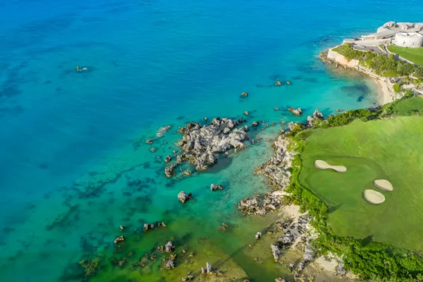 Aerial view of an oceanfront hole at Five Forts golf course, with a fort behind the green
