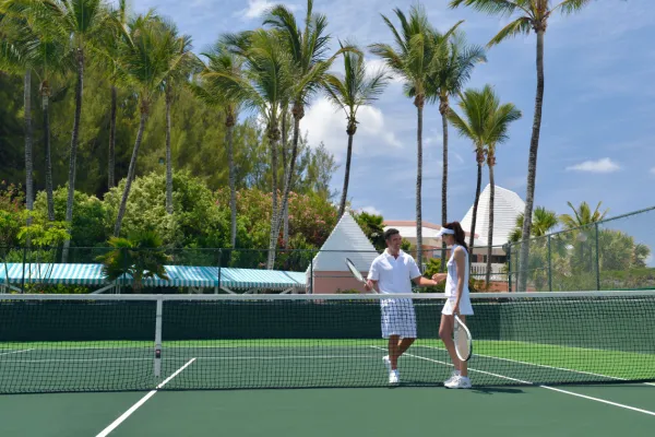 Two people converse on a Bermuda tennis court
