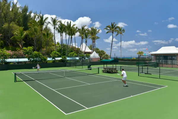 Two people rallying at a palm tree lined tennis court in Bermuda