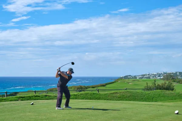 A man tees off on a Bermuda golf course