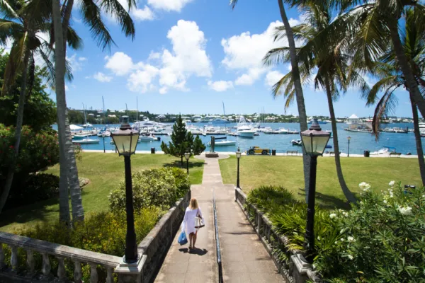 Woman walks down a path towards a yacht dock yard