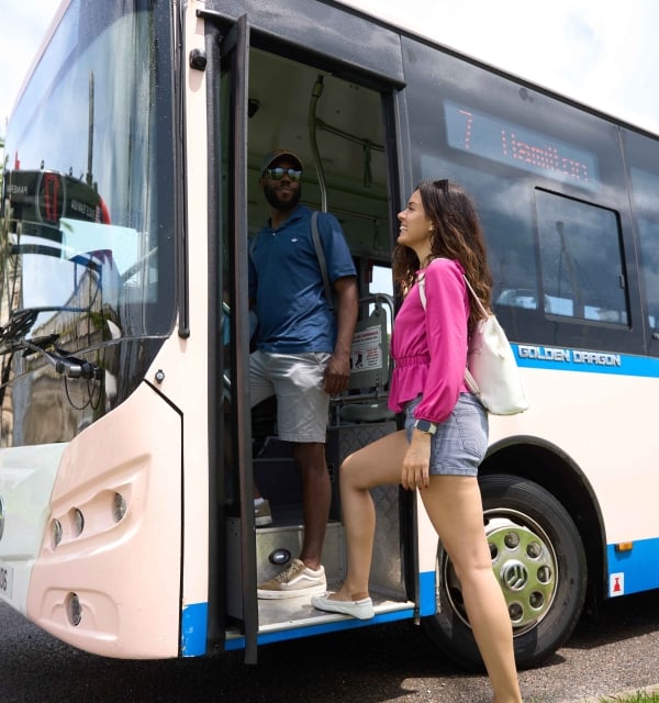 Two people are hopping on the Bermuda bus.
