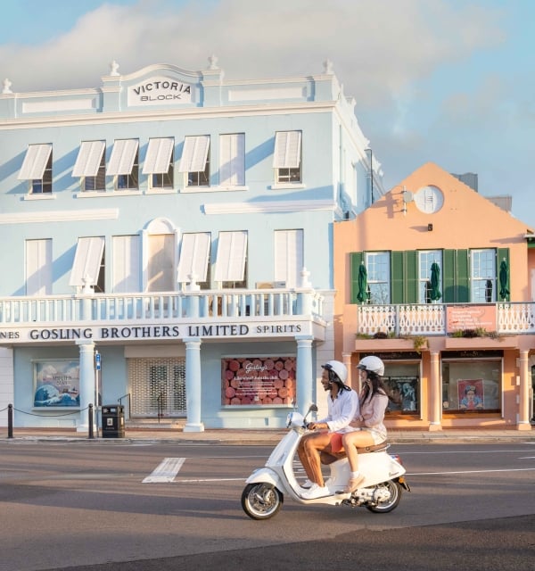 Two people are driving down Front Street on a Scooter