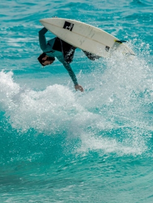 Man surfing on the ocean doing a flip on the wave