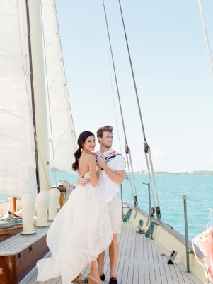 A bride and groom on the bow of a sailboat 