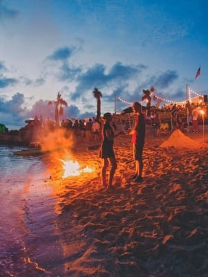 People standing on the beach next to a bonfire at Tobacco Bay