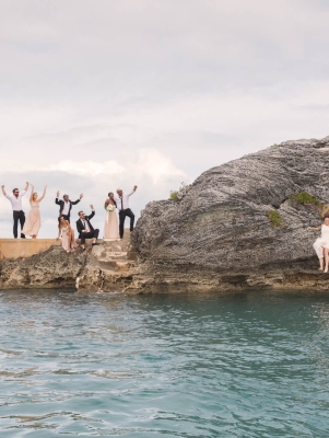 Couple jumping into water with people watching