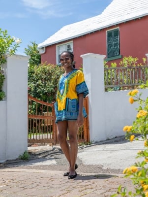 Young woman standing in front of a brightly coloured house