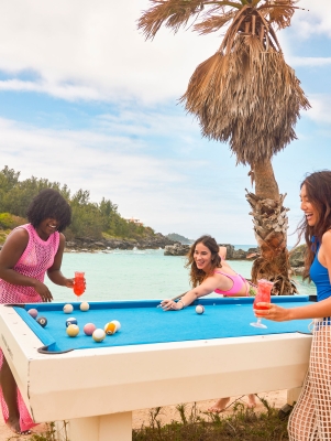 Three friends are playing pool on the beach.