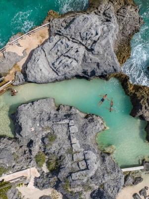 An aerial of people in a natural sea pool. 