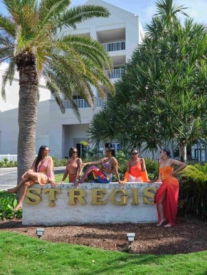 A group of friends are sitting on the St. Regis Bermuda hotel sign.