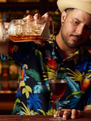 A man is pouring a cocktail into a glass.