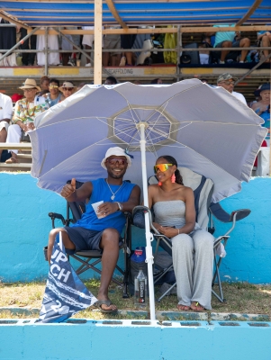 A couple is sitting under a tent court side at Cup Match.