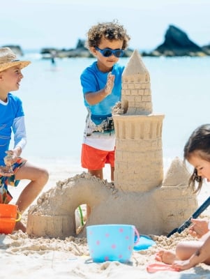 A group of kids are playing in the sand at the Hamilton Princess Beach Club