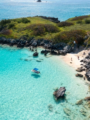 A family is on a beach with a boat anchored just a short ways off.