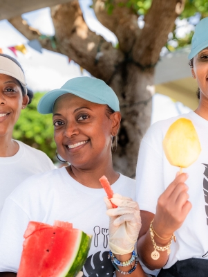 Three women are smiling holding fruit.