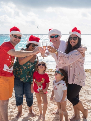 A family is cheering while on the beach in Christmas gear.