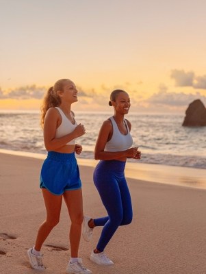 Two girls are running on the beach.