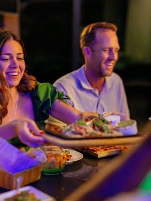 A woman is passing a plate of food around.