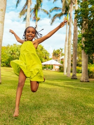 A little girl is running in the grass.