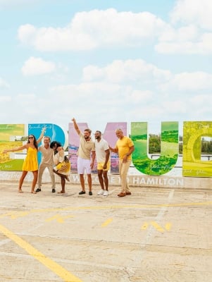 A group are posing in front of the Bermuda sign.