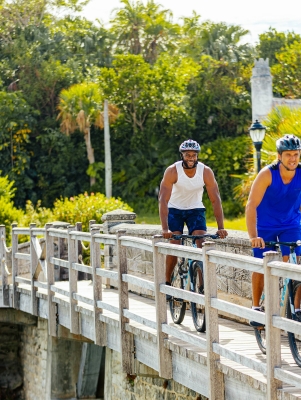 Two men biking by the smallest drawbridge.