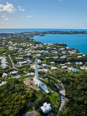 Aerial view of Gibbs Hill Lighthouse with calm waters and blue skies. 