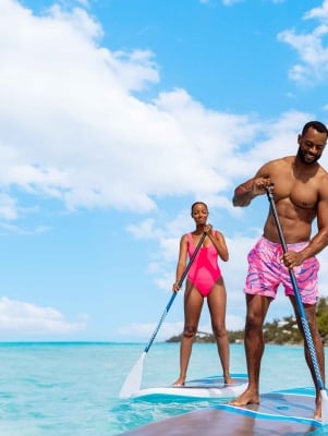 A couple are paddle boarding.