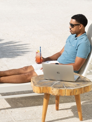 A man is sitting on a lounge chair by a lounge chat.