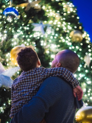 A father and son are posing by a christmas tree.