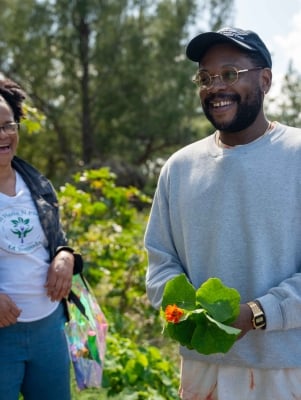 Two people are smiling holding plants