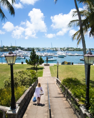 Woman walks down a path towards a yacht dock yard