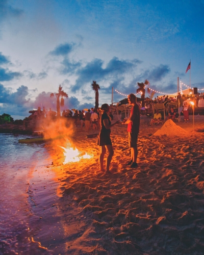 People standing on the beach next to a bonfire at Tobacco Bay