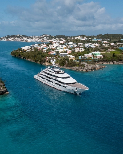 A large super yacht is exiting the channel on calm blue waters. 