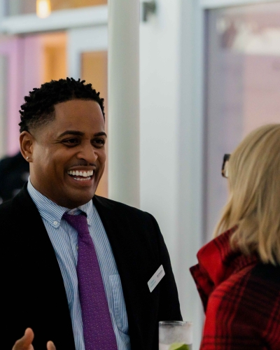 A man is smiling while talking to a woman.